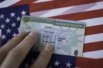 Permanent Resident Green card of United states of America on flag of USA. Above close up view.